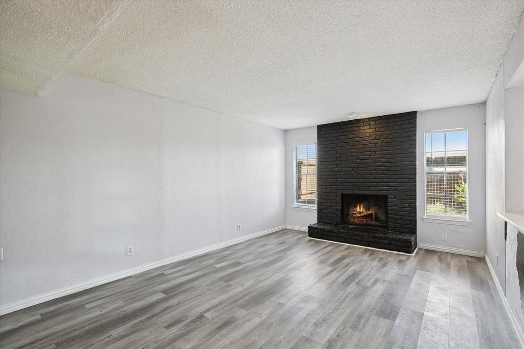 Living area featuring wood-finish flooring and a floor-to-ceiling painted brick fireplace with a raised masonry hearth