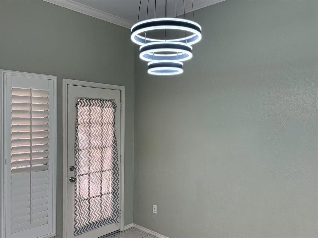 Multi-tiered LED ring chandelier, white louvered plantation shutters, and glass-paneled exterior door