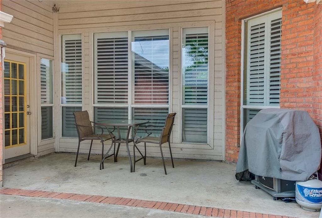 Covered patio featuring a concrete floor with brick border detailing, brick and siding exterior, and multi-pane windows equipped with interior shutters