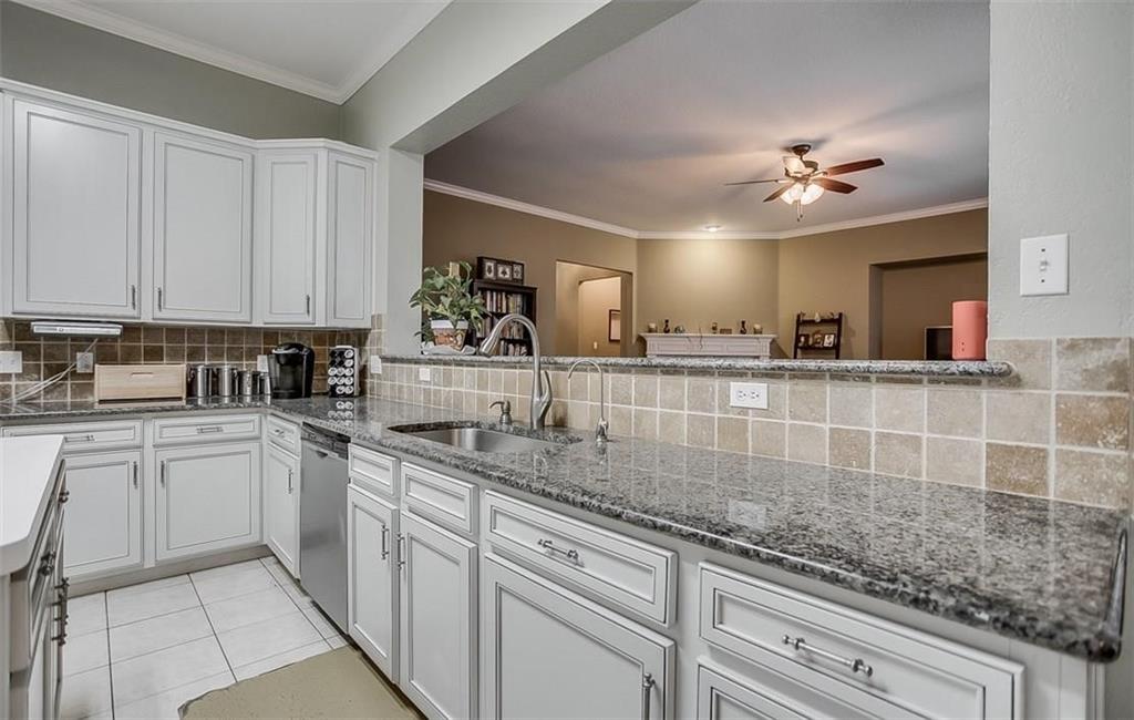 Kitchen featuring white cabinetry, stone countertops, square-tile backsplash, stainless steel sink, and stainless steel dishwasher