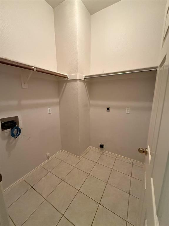 Utility area featuring ceramic tile flooring, built-in shelving, and dedicated washer and dryer hookups