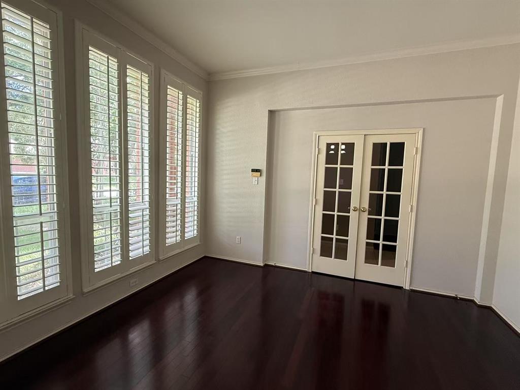Wood-finish flooring, multi-pane glass French doors, and oversized windows featuring custom plantation shutters
