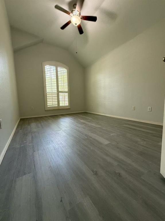 Vaulted ceilings featuring wood-finish flooring, an arched window with plantation shutters, and a central ceiling fan