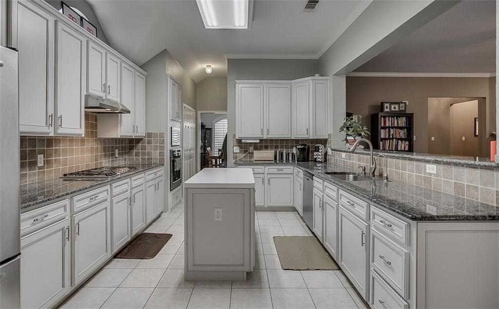 Kitchen featuring white cabinetry, stone-surface countertops, central island, tiled backsplash, and stainless steel appliances