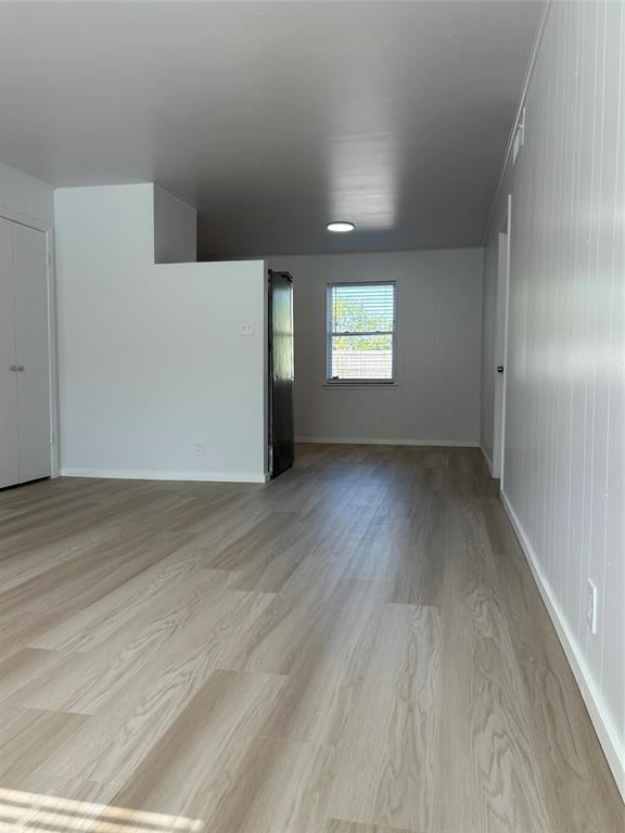 Neutral interior featuring light-tone wood-finish flooring, crisp white walls, and a recessed ceiling light fixture