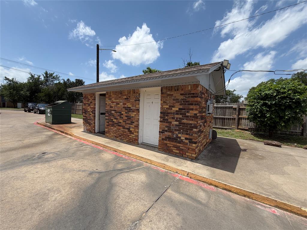 Multi-tone brick exterior featuring a shingle roof, two solid-panel entry doors, and concrete paving