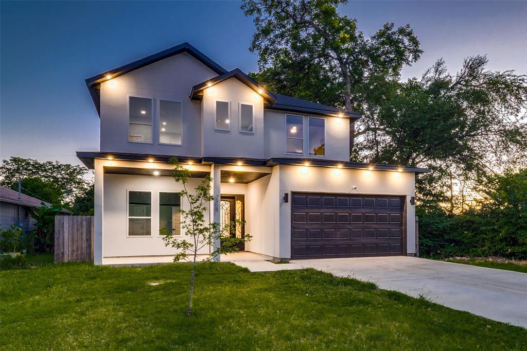Two-story stucco exterior featuring a gabled roofline, concrete driveway, attached multi-car garage, and recessed exterior lighting