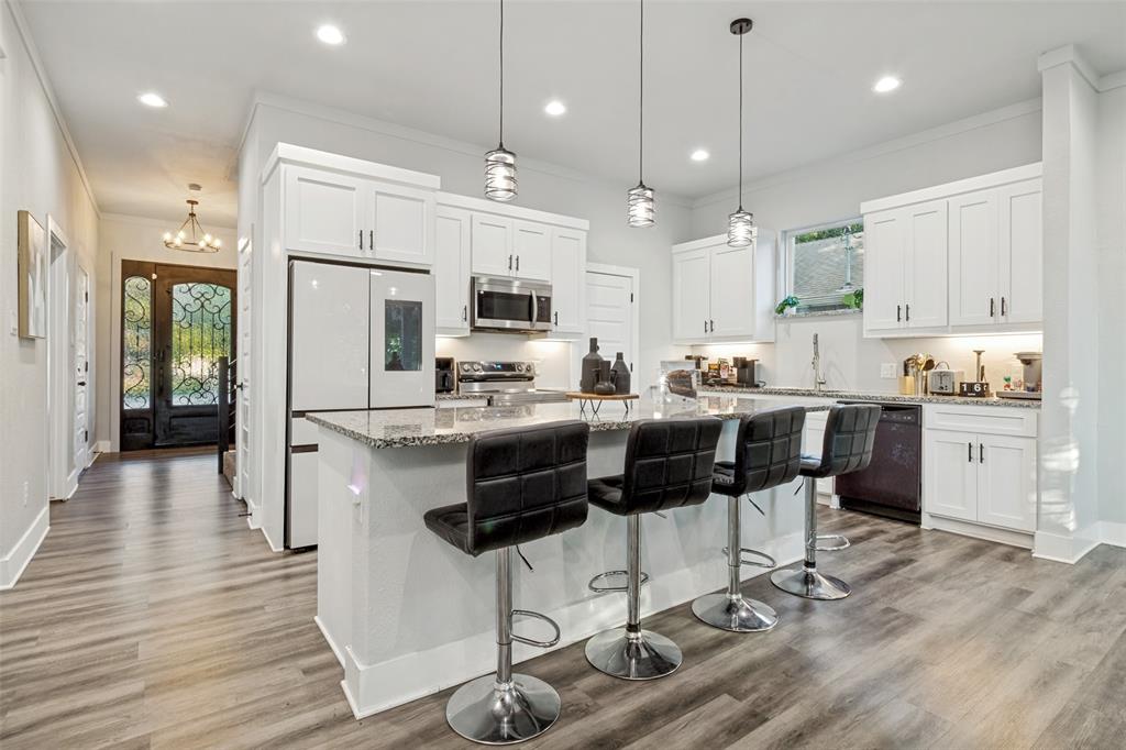 Kitchen featuring white cabinetry, stone countertops, an expansive center island, recessed lighting, and wood-finish flooring