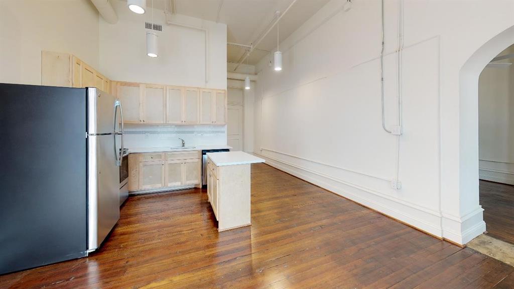 Kitchen featuring backsplash, dark wood-type flooring, stainless steel refrigerator, and a kitchen island