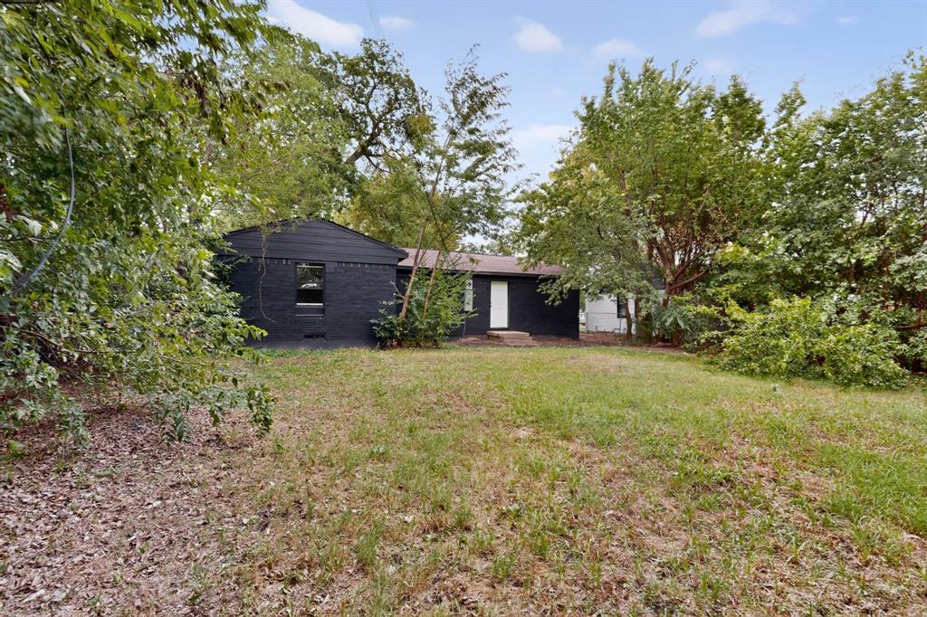 Exterior featuring a dark-painted brick facade, gabled roofline, and expansive grounds with mature trees