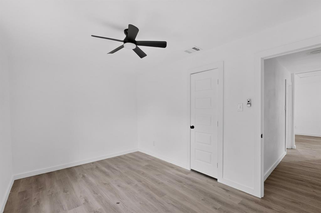 Interior space featuring wood-finish flooring, a five-panel interior door, and a matte black ceiling fan with integrated lighting