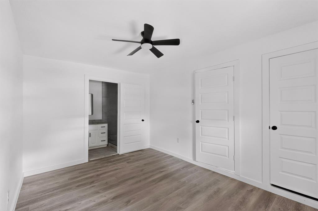 Interior space featuring wood-finish flooring, a matte black ceiling fan, and three-panel interior doors with matte black hardware