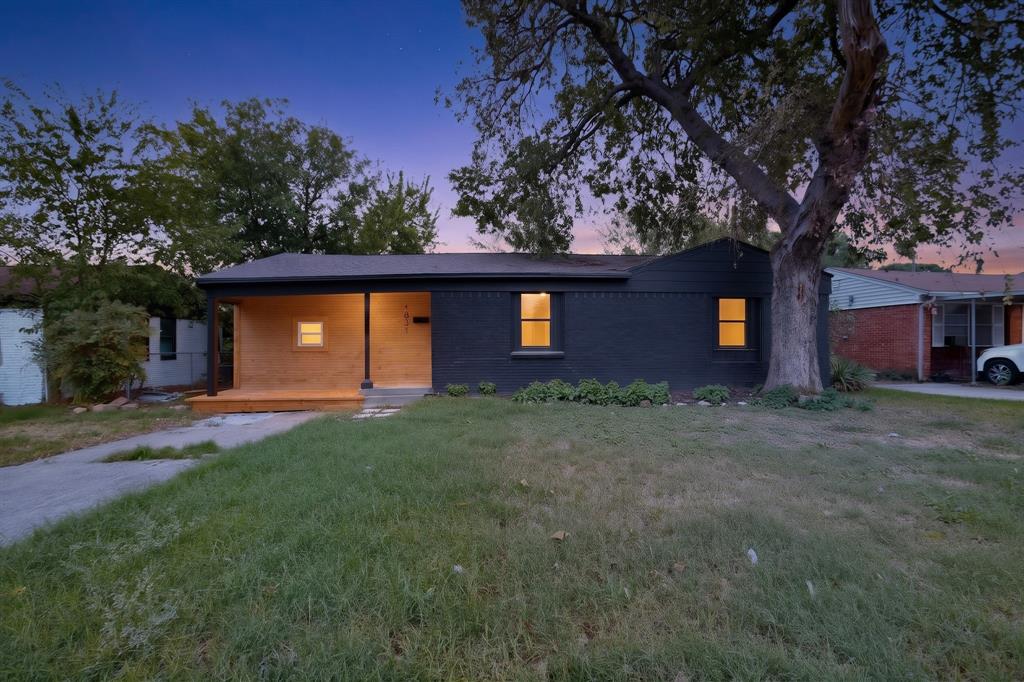 Single-story residence featuring a painted brick exterior, natural wood-paneled porch, covered entry, and mature landscaping
