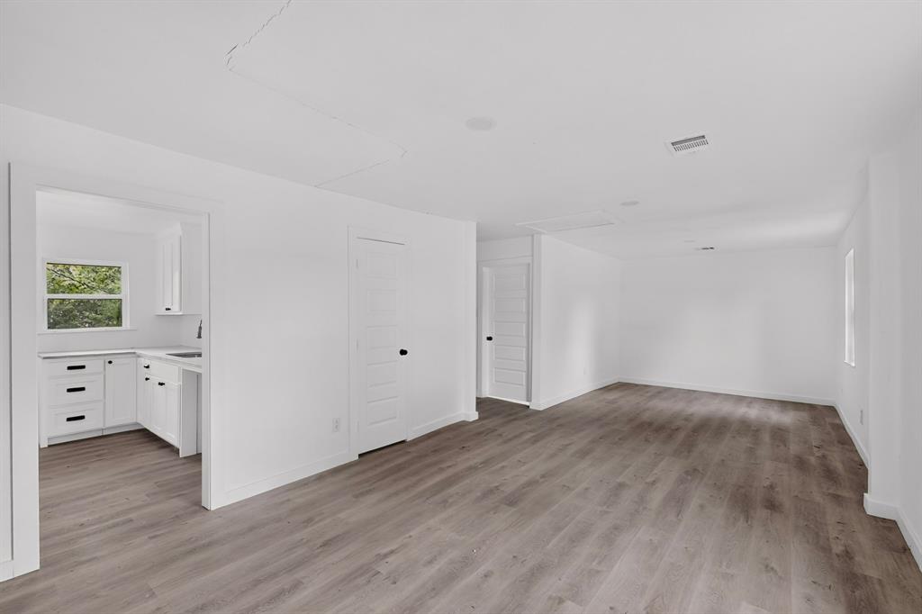 Interior space featuring wood-finish flooring, white shaker-style cabinetry, matte black hardware, and multi-panel interior doors