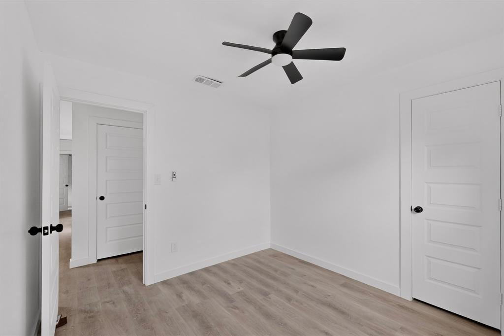 Interior space featuring wood-finish flooring, five-panel shaker-style doors with matte black hardware, and a modern matte black ceiling fan with an integrated light fixture