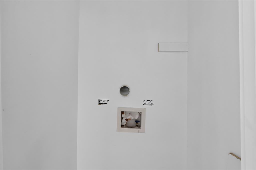 Utility area featuring a recessed plumbing box, integrated water supply valves, and an exhaust vent