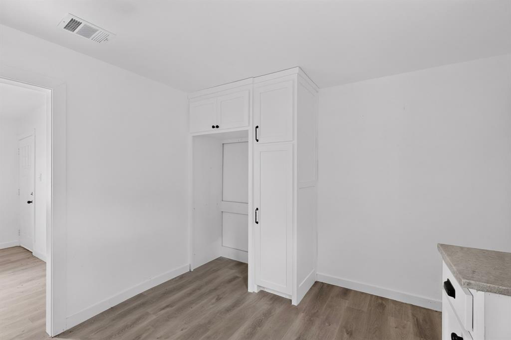 Custom white built-in cabinetry featuring shaker-style doors, matte black hardware, and wood-finish flooring