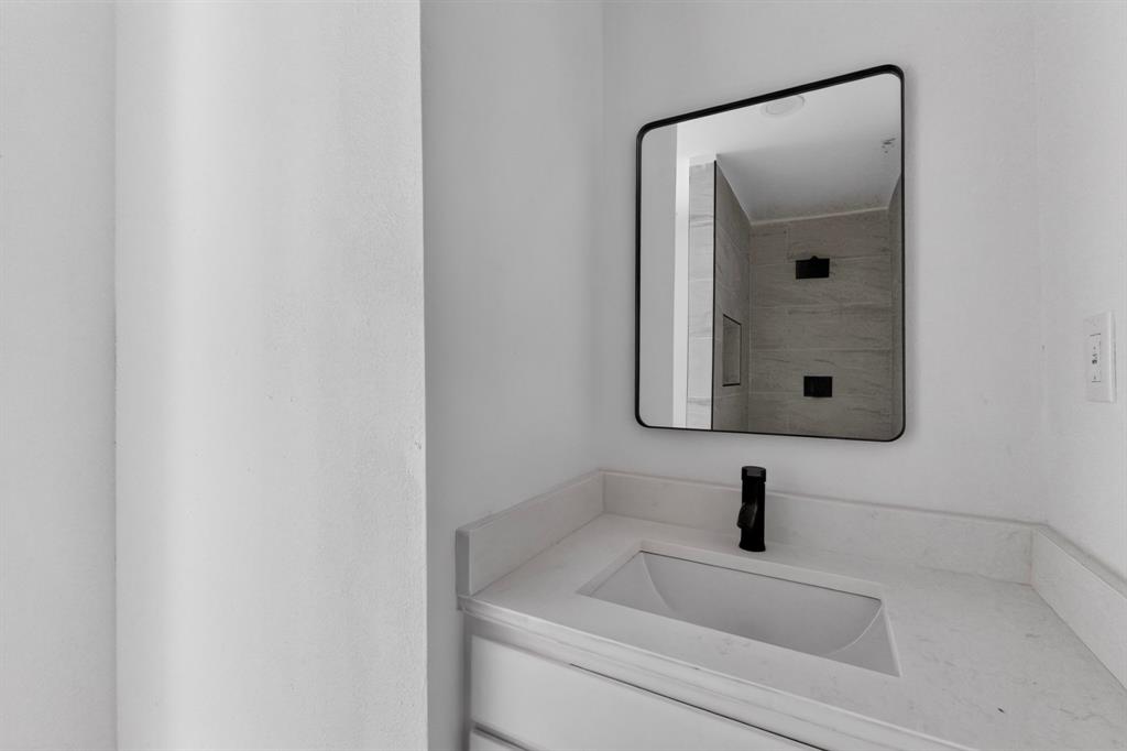 Vanity featuring a solid-surface countertop with an integrated rectangular sink and matte black faucet, paired with a square-cornered mirror in a black frame