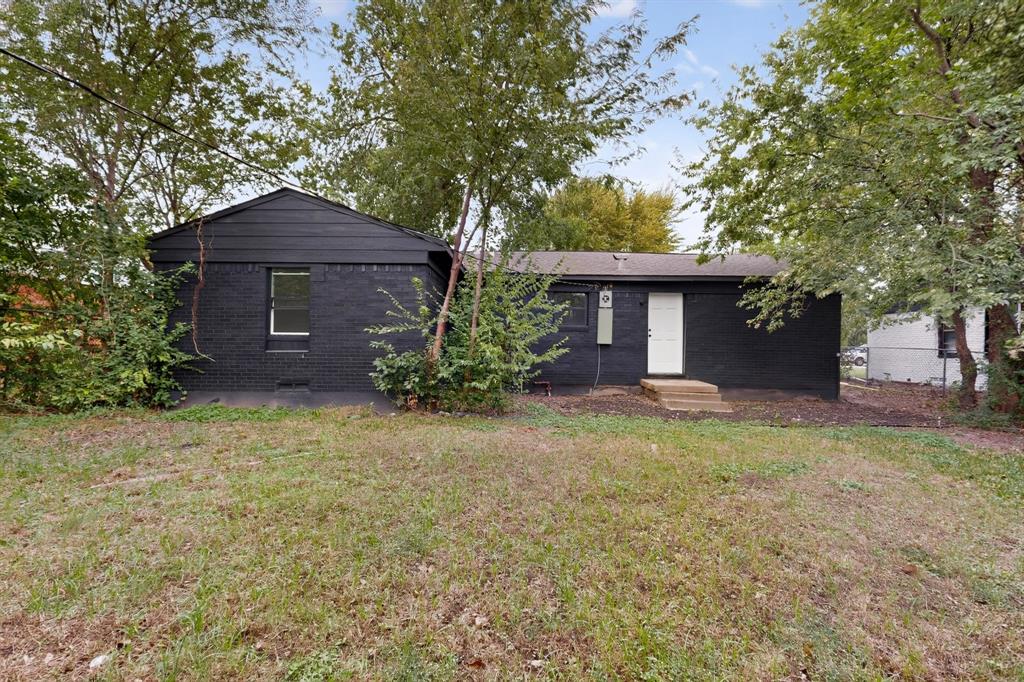 Exterior featuring a black-painted masonry finish, horizontal siding gable, single-entry door, and mature surrounding trees