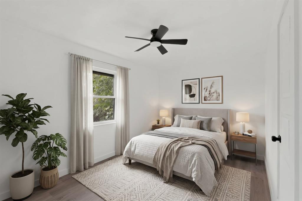 Room featuring wood-finish flooring, a matte black ceiling fan with integrated lighting, and a window with neutral-toned hardware