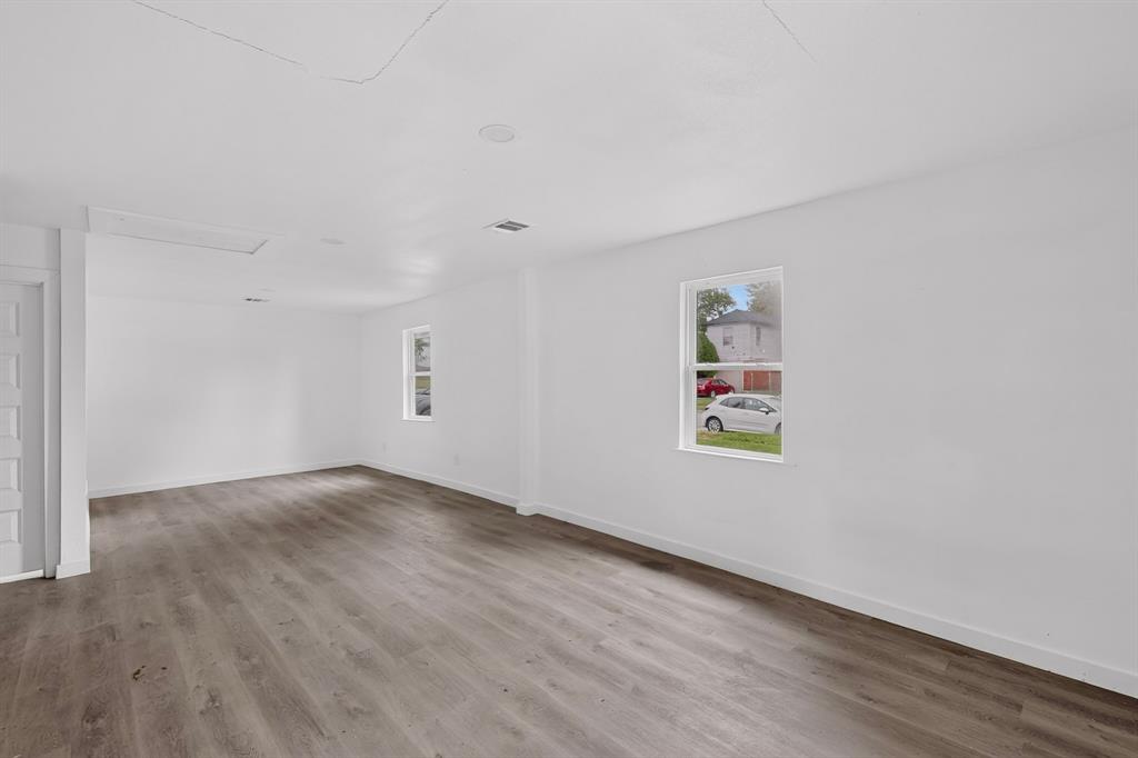 Neutral interior featuring wood-finish flooring, white walls, and multiple single-hung windows