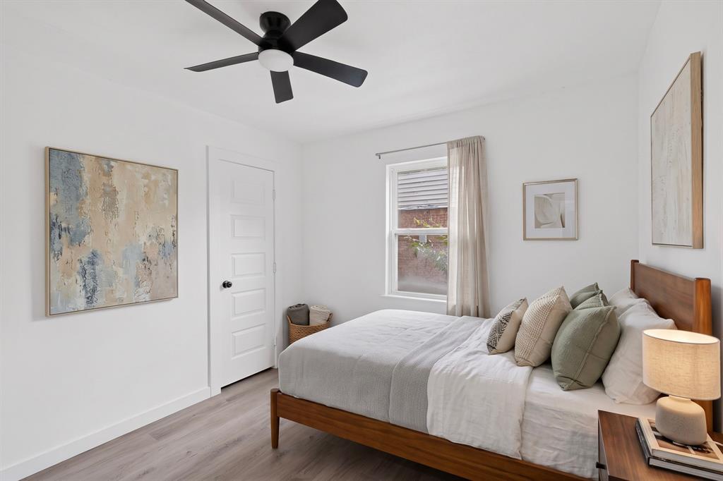 Interior space featuring wood-finish flooring, a five-panel interior door, and a matte black ceiling fan with an integrated light fixture