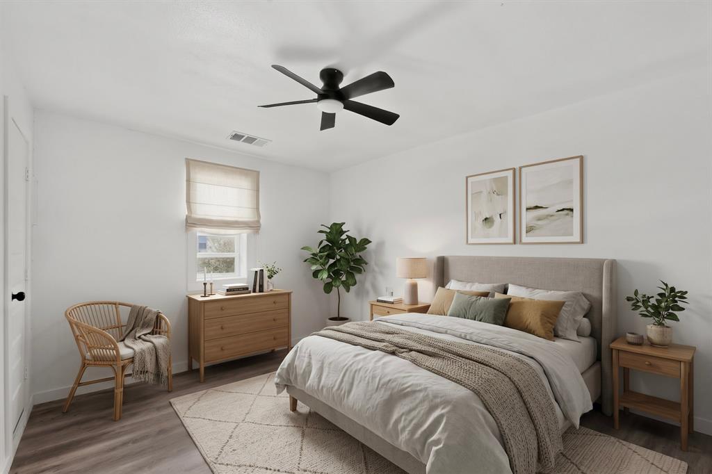 Neutral-toned room featuring wood-finish flooring, a matte black multi-blade ceiling fan with integrated lighting, and a window with a fitted fabric roman shade