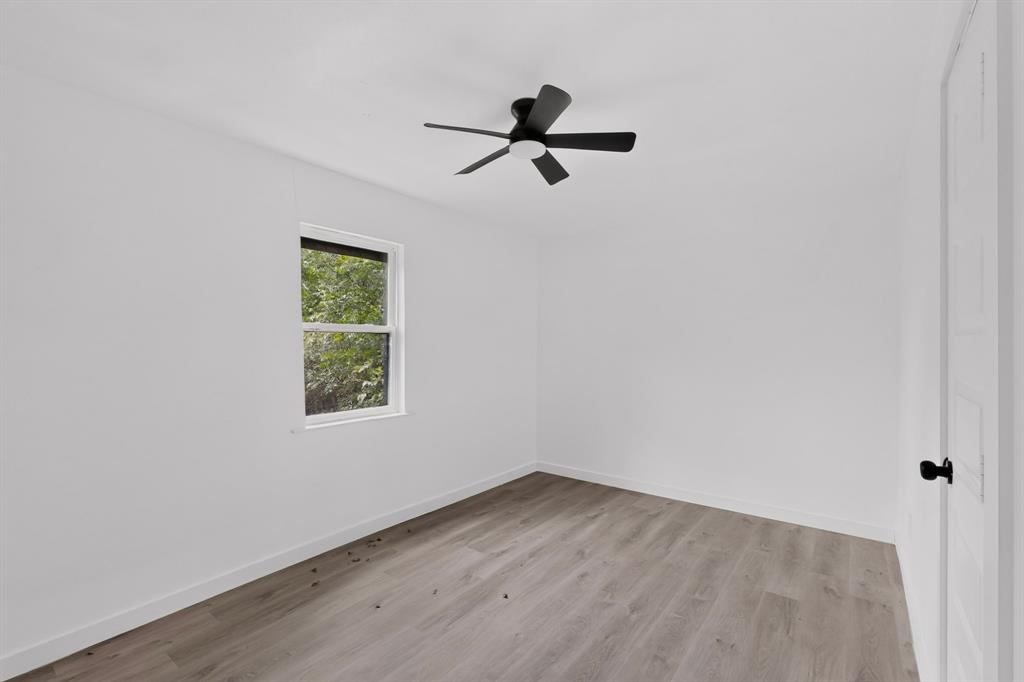 Neutral-toned wood-finish flooring, white walls, and a modern ceiling fan with matte black finish
