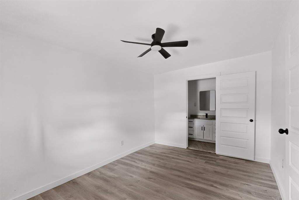 Neutral interior featuring wood-finish flooring, a matte black ceiling fan with integrated lighting, and a five-panel interior door