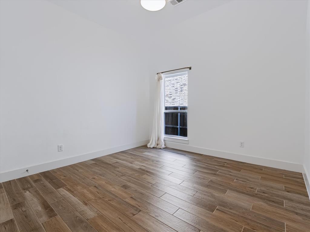 Interior room featuring wood-finish tile flooring, white walls, and a single window with a white frame