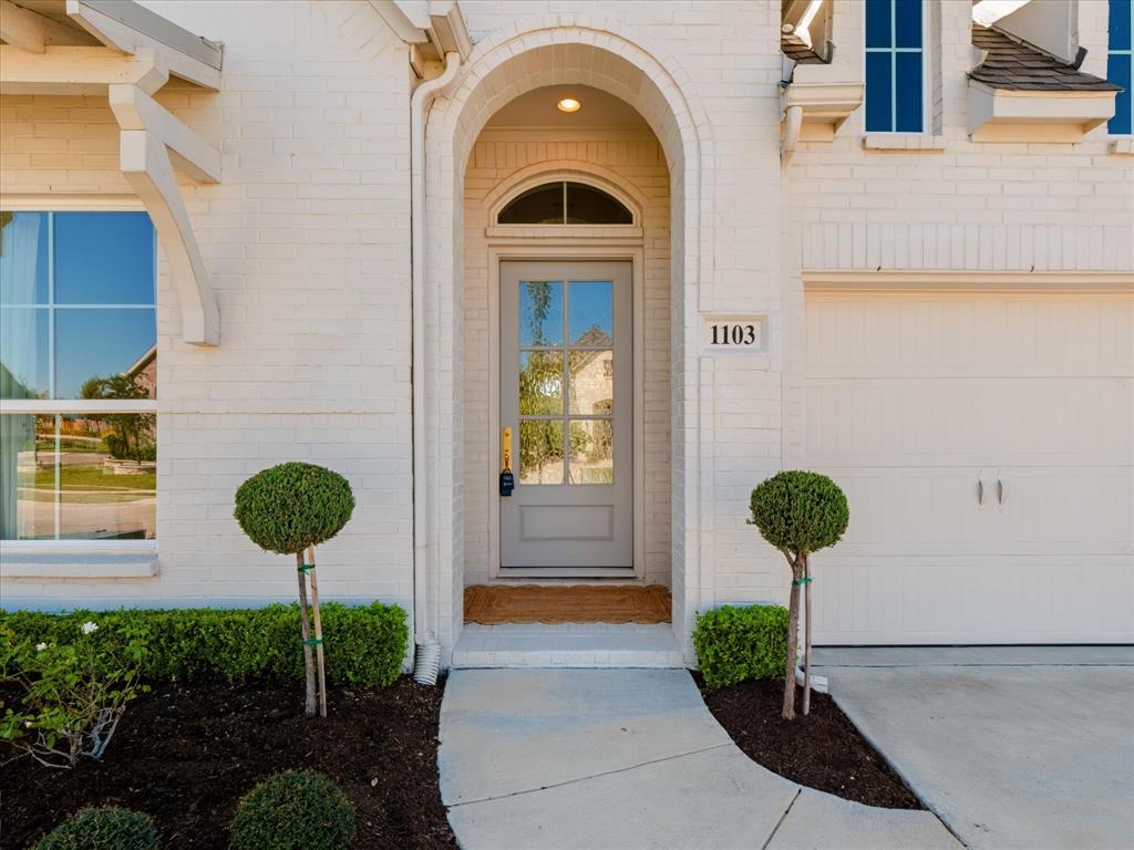 Painted brick exterior with an arched entryway, transom window, six-pane glass front door, and concrete walkway
