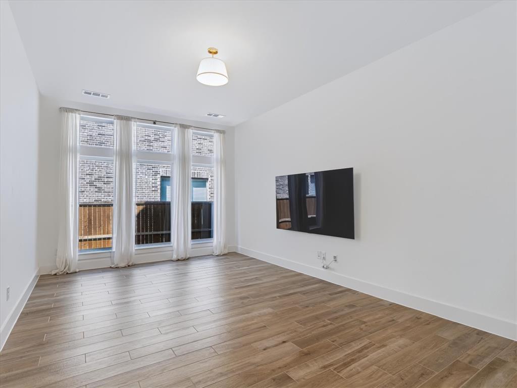 Wood-finish flooring, floor-to-ceiling windows, and a central pendant light fixture