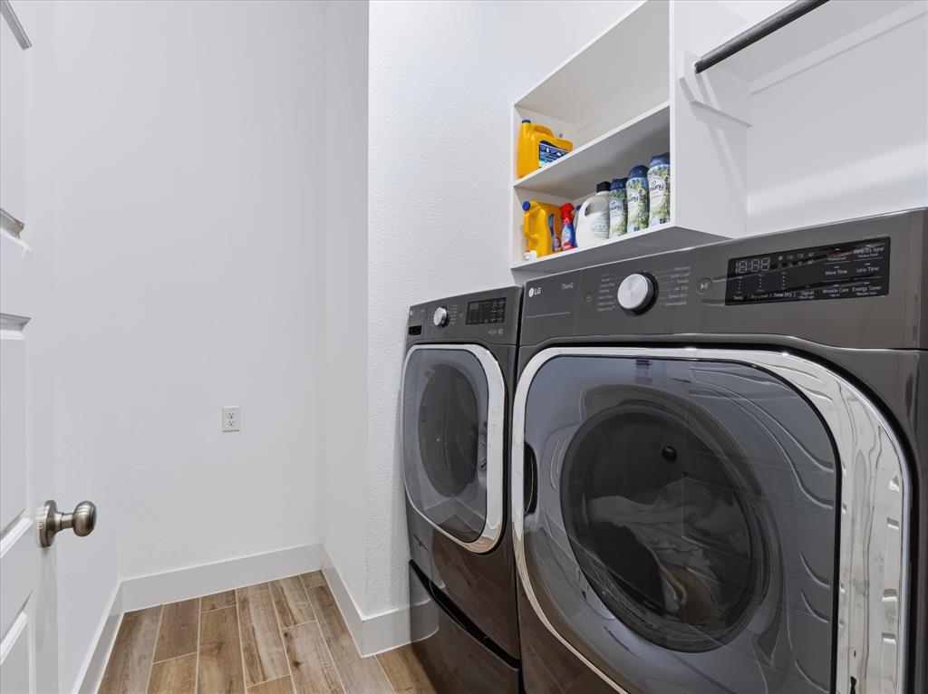 Laundry area featuring wood-finish tile flooring, built-in white overhead shelving, and a metal hanging rod