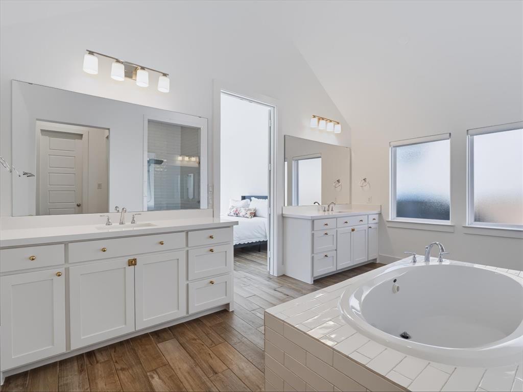 Dual white vanities featuring shaker-style cabinetry, white countertops, and large wall-mounted mirrors