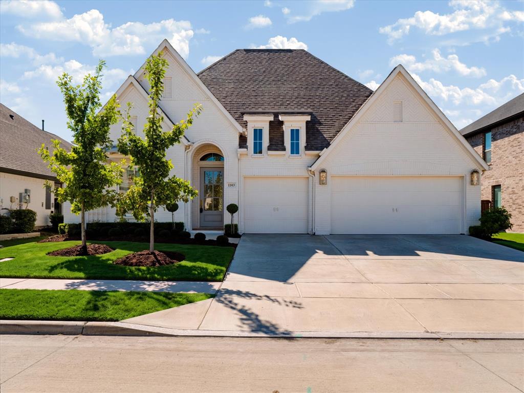 Brick exterior with a gabled roofline, arched entryway, and three-car garage