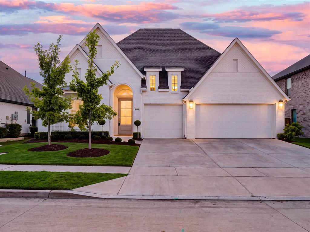 White brick exterior featuring a multi-gabled roofline, an arched entryway, and an attached three-car garage