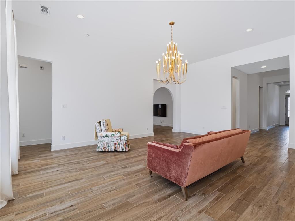 High ceilings featuring recessed lighting, expansive wood-finish flooring, and an ornamental tiered metal chandelier