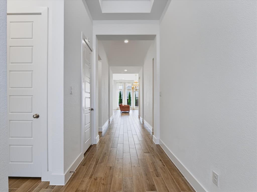 Hallway featuring wood-finish flooring, recessed lighting, a recessed ceiling detail, and five-panel interior doors