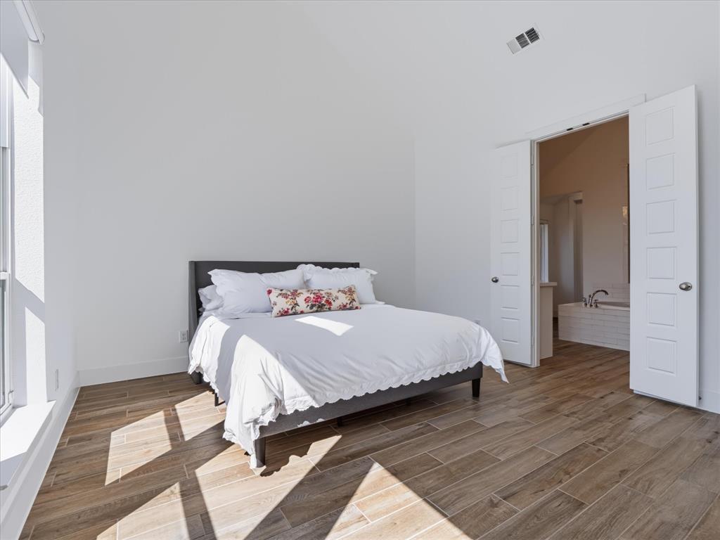 High-ceilinged room featuring wood-finish flooring, double-panel doors, and natural light from a side window