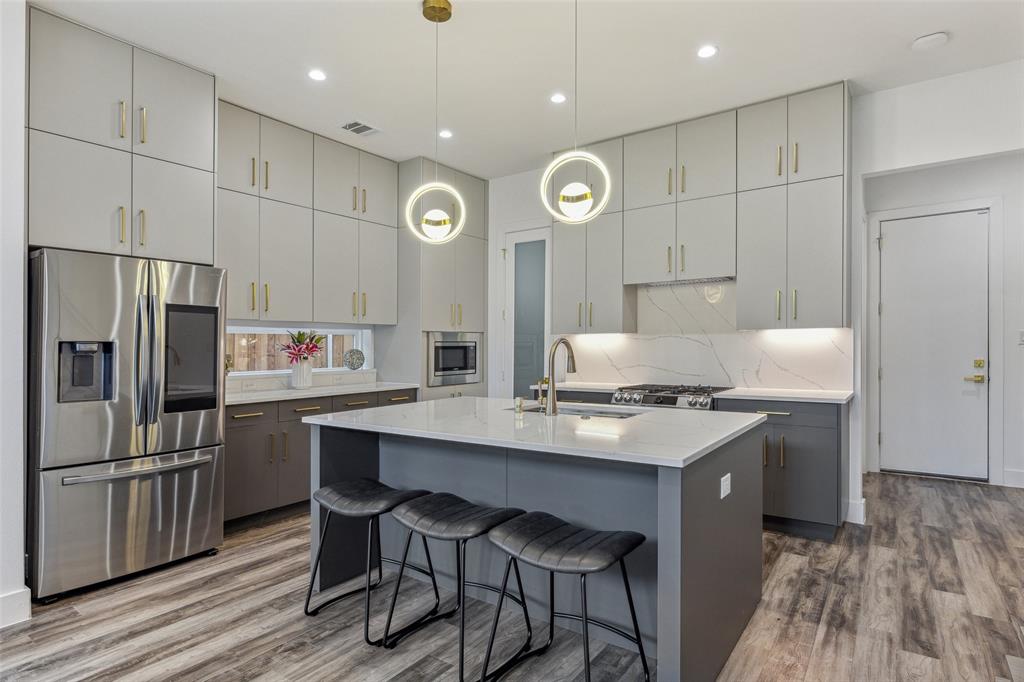 Kitchen with appliances with stainless steel finishes, a center island with sink, hardwood / wood-style flooring, and sink