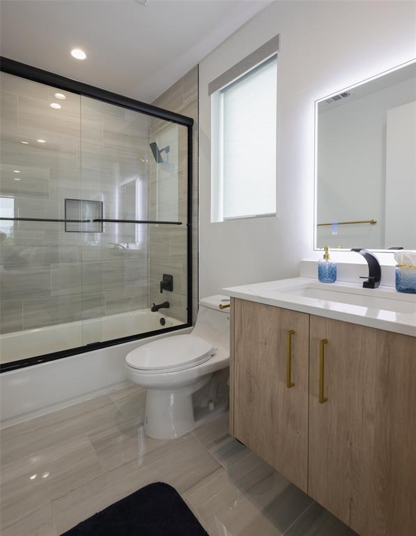 Full bathroom featuring enclosed tub / shower combo, tile patterned flooring, vanity, and toilet
