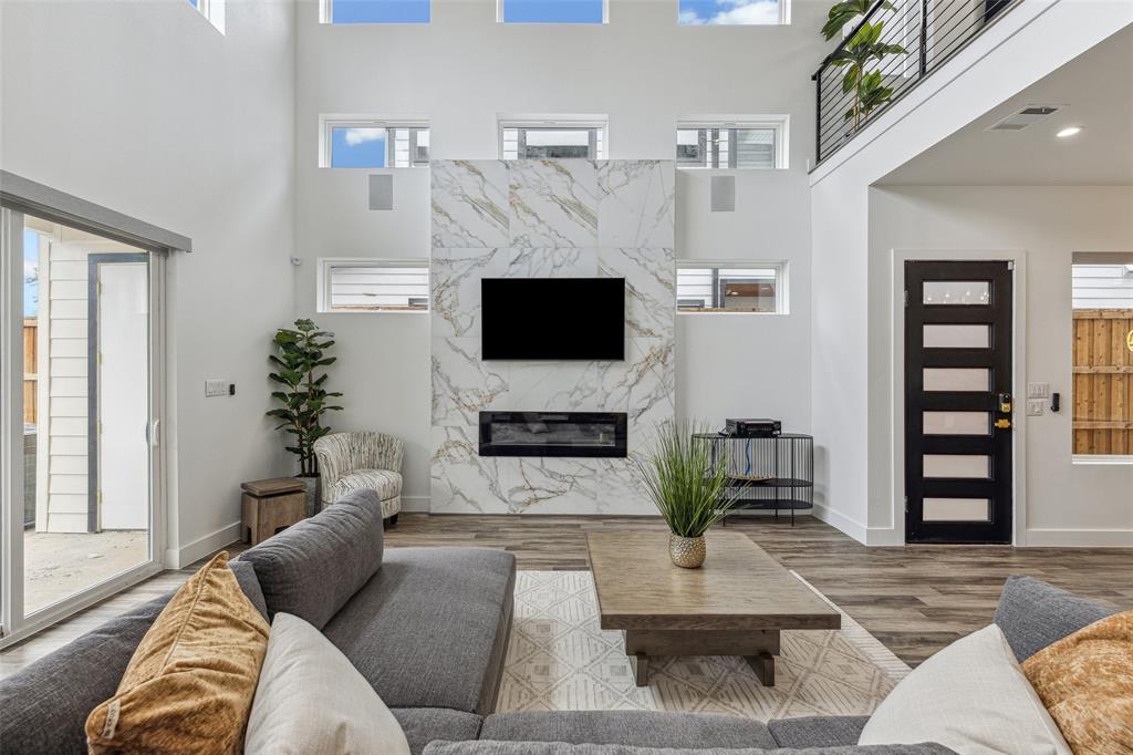 Living room with a high ceiling, a high end fireplace, and wood-type flooring