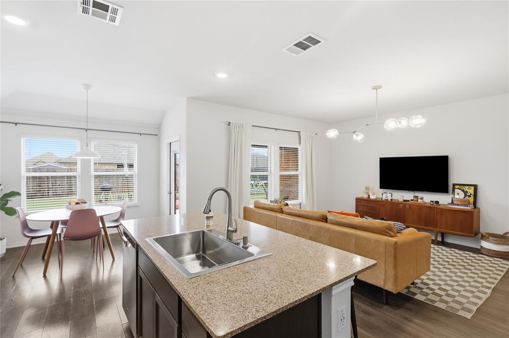 Kitchen featuring a stone-surfaced center island, stainless steel undermount sink, dark-finish cabinetry, recessed lighting, and wood-finish flooring