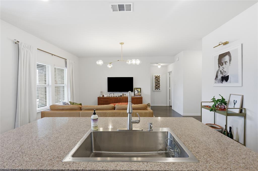 Kitchen island featuring stone countertop, under-mount stainless steel sink, and high-arc pull-down faucet