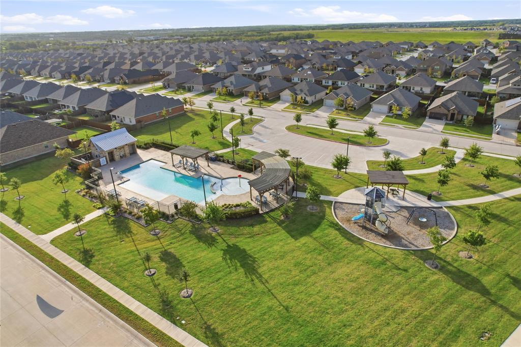 Community amenities featuring an outdoor swimming pool, stone-clad poolside structure, multiple shaded pergolas, and a paved playground area set within landscaped grounds