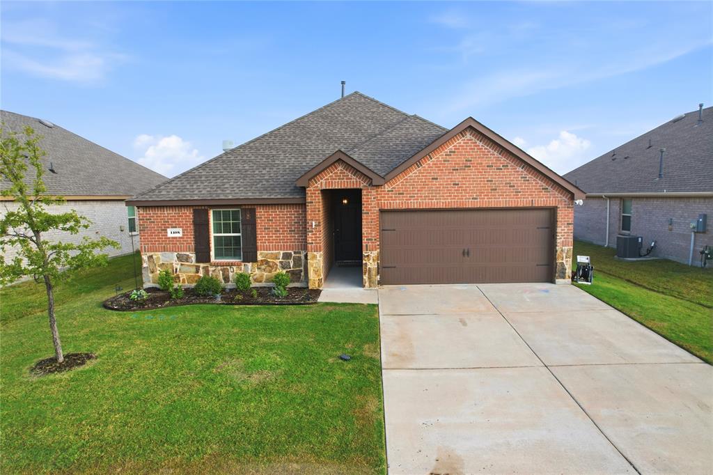 Brick and stone facade exterior featuring a multi-gabled roofline, an attached two-car garage with a panel door, and concrete driveway