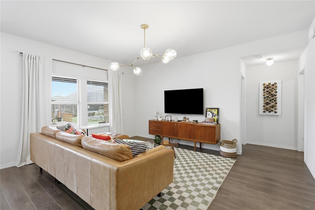 Neutral-toned living space featuring wood-finish flooring, a multi-globe pendant light fixture, and dual windows