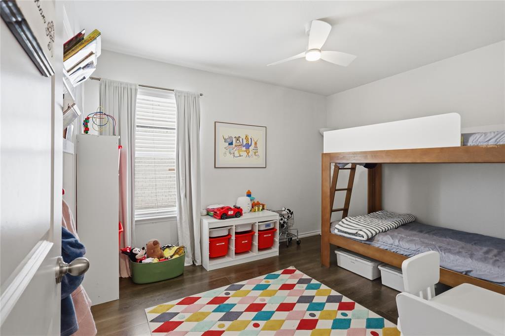 Room featuring wood-finish flooring, a contemporary three-blade ceiling fan with integrated lighting, and a window with horizontal blinds