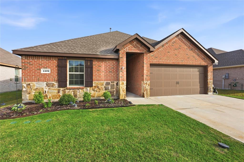 Brick and stone veneer exterior with decorative shutters, a covered entryway, and an attached two-car garage