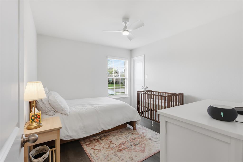 Neutral interior space featuring wood-finish flooring, a single-hung window with a grid pattern, and a ceiling-mounted light fixture with an integrated fan